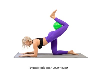 Exercise leg kicks with small fit ball. Athletic beautiful woman stand on all fours on a mat and practice pilates with props, isolated on white.