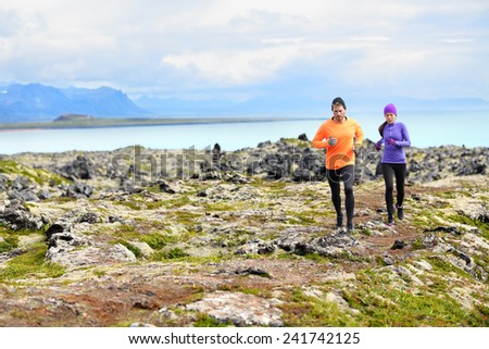 Exercise running sport. Runners on cross country trail run outdoors working out. Fit young fitness model man and asian woman training together outside in mountain nature on Snaefellsnes, Iceland.