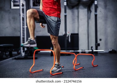 Exercises with hurdles. Close-up shot of a man’s legs in sportswear that skips small hurdles. Jumping over obstacles and warming up for training. Healthy lifestyle, strong movement, dynamism