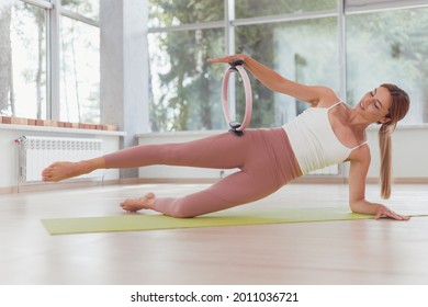 Exercises with pilates ring. Woman doing aerobics workout at sport gym with panoramic windows. - Powered by Shutterstock