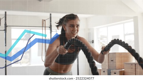 Exercising with battle ropes, woman over data graph image in gym. Fitness, exercise, workout, training, technology, health - Powered by Shutterstock