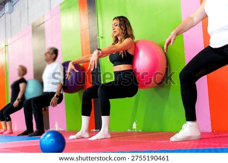 Exercising group doing wall squats with stability balls, an effective gym workout for fitness and strength