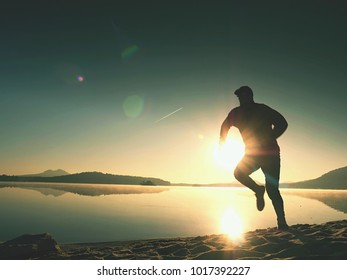 Exercice sur la plage du lac au coucher du soleil, grand soleil à l'horizon