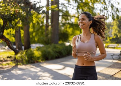 Exercising outdoors is healthy for active lifestyle runners. Autumn trail run woman running in nature from behind in dark forest. Outdoor jog. Pretty sporty woman jogging at park in sunrise light - Powered by Shutterstock