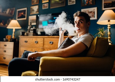 Exhaling The Vapor With Electronic Cigarette.Puffing Clouds Of Smoke.Vape Flavor Liquid Chemicals.Use Of E-cigarettes In The Home.Smoking And Vaping Negative Health Effects.Nicotine Addiction Habit