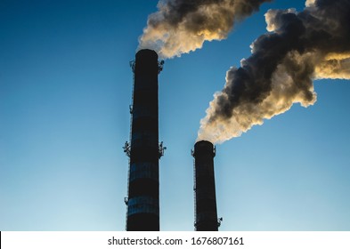 Exhaust Fumes Blown Into A Sky. Smoke From Industrial Chimneys Against A Blue Sky. Smoke From Factory Chimneys In An Urban Environment. Concept: Environmental Pollution, Ecology