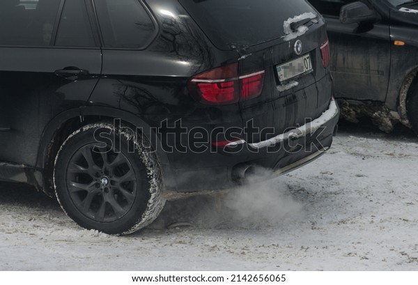 exhaust fumes coming out of\
the car, running the car smokes, warming up the car on a cold day,\
black bmw