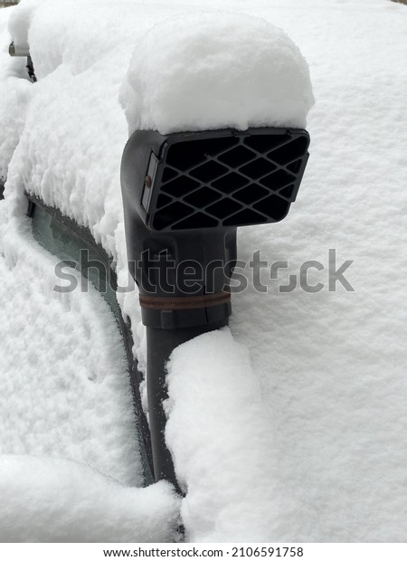 Exhaust pipe of the car sticks out from under the snow.\
Cars buried in the snow. Auto under snow in winter snow storm\
outdoors. 