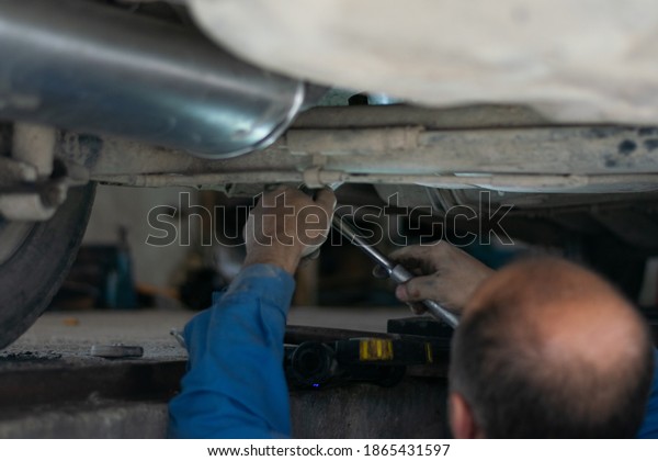 Exhaust pipe service car mechanic repairs and\
puts new rear muffler