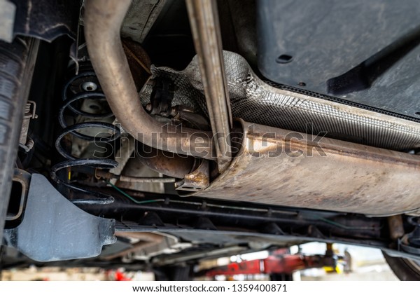 The exhaust system in the car seen\
from below, the car is on the lift in the car\
workshop.