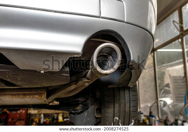 The exhaust\
system in the car seen from below, visible exhaust tip,  the car is\
on the lift in the car\
workshop.