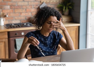 Exhausted African American Young Woman Work On Laptop At Home Office Struggle With Migraine Or Headache. Tired Biracial Female Employee Suffer From Blurry Visions Or Dizziness Overwork On Computer.