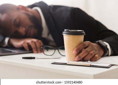 Exhausted African Business Clerk Holding Cup Of Coffee And Sleeping At Workplace, Burnout Concept