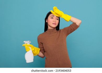 Exhausted Asian Housekeeper Stressed And Angry From Chores, Holding Spray Detergent Feeling Tired Frustrated And Negative. Overwhelmed Housework Housewife From Day To Day Chores