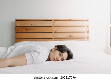 Exhausted Asian Man Lay On The Bed As He Feels Burnout.