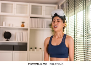 Exhausted Asian woman use innovative technology VR glasses for exercise. Attractive beautiful girl wearing virtual reality headset feel tired after doing boxing fight workout for health care at home. - Powered by Shutterstock