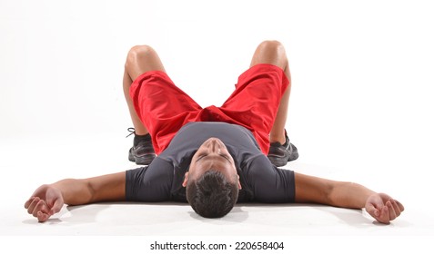 Exhausted athletic man lying down on white background.