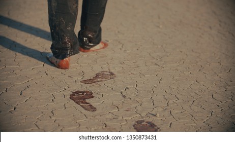 Exhausted Barefoot Man Walking In Desert And Making Bloody Footsteps Before Falling In The End. Blood Stains, Bloody Footprints, Desert Foot Prints. Thriller In 4k With Warm Color Correction.