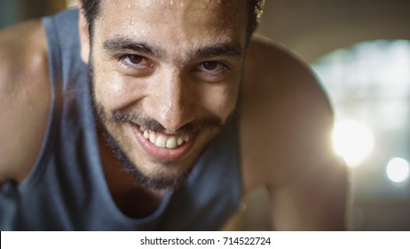 Exhausted Bend Muscular Man Looks Into Camera And Rests After Intensive Workout. He's In A Gym And Covered In Sweat. He Tries To Catch A Breath.