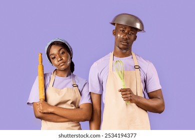 Exhausted black couple with kitchen utensils having hard time baking on violet background - Powered by Shutterstock