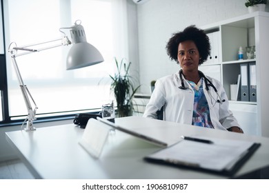 Exhausted Black Female Doctor Sits At Her Office Taking Break