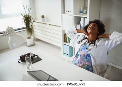 Exhausted Black Female Doctor Sits At Her Office Taking Break