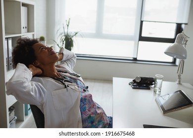 Exhausted Black Female Doctor Sits At Her Office Taking Break