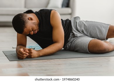Exhausted Black Fitness Man Feeling Bad During Workout Exercising On Floor At Home. Sport And Health Problems. Healthcare And Medical Restrictions For Training Routine Concept - Shutterstock ID 1974860240