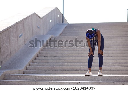 exhausted black fitness woman fizzle out, standing on stairs outdoors. after running