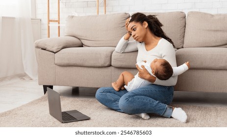 Exhausted Black Mother Holding Crying Baby And Touching Head Suffering From Headache Sitting At Laptop On Floor At Home. Motherhood Burnout Concept. Tired Mother Posing With Shouting Child - Powered by Shutterstock