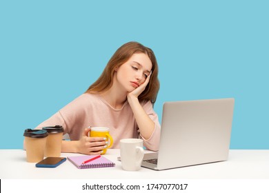 Exhausted bored woman, office employee surrounded by coffee cups in workplace, looking at laptop screen with indifferent apathetic face, overtime work. indoor studio shot isolated on blue background