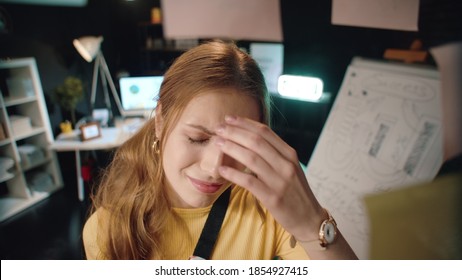 Exhausted Business Woman Touching Forehead At Workplace. Stressed Girl Suffering From Headache In Dark Office. Tired Lady Sighing Heavily In Front Of Glass Wall In Late Coworking.