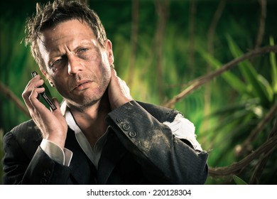 Exhausted Businessman In The Jungle With Neck Pain Holding Mobile Phone.