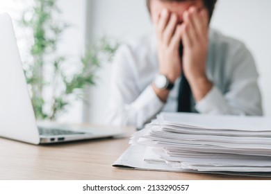Exhausted businessman overloaded with work in office, selective focus