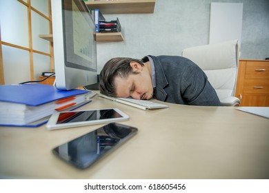 The exhausted businessman is sleeping on the keyboard of a computer. He was working a lot.