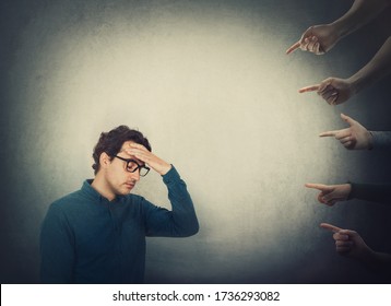 Exhausted businessman suffers dizziness, feels discomfort as multiple people hands pointing to him blaming as guilty. High tension and pressure, depression and emotional stress. Social victim concept. - Shutterstock ID 1736293082