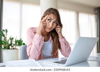 Exhausted businesswoman having a headache in modern office. Creative woman working at office desk feeling tired. Stressed casual business woman feeling head pain while overworking on desktop computer.
