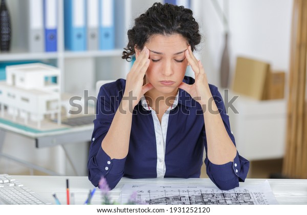 exhausted\
businesswoman in her office with head in\
hands