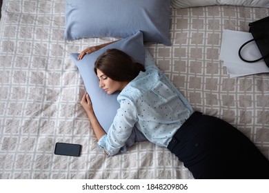 Exhausted businesswoman in office wear sleeping on bed at home after work, above view - Powered by Shutterstock