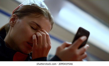 Exhausted Doctor Using Mobile Phone. Portrait Of Professional Paramedic Feeling Tired After Work During Night Shift. Closeup Female Medic Taking Off Protective Glasses. Woman Touching Face With Hand 