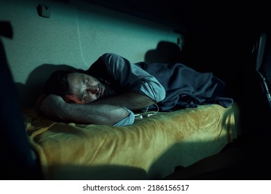 Exhausted Driver Sleeping On A Bed In Truck Cabin At Night.