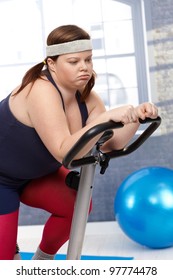 Exhausted Fat Woman Sitting On Exercise Bike After Workout.