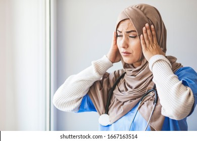 Exhausted Female Muslim Doctor Taking A Break. Shot Of A Young Female Nurse Looking Stressed Out While Standing At A Window In A Hospital. It's A Stressful Profession