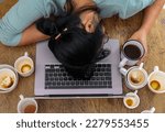 Exhausted female worker surrounded by coffee cups sleeping at workplace over laptop. Tired over work woman having too much work and coffee, napping on laptop. Caffeine addicted bad lifestyle concept.