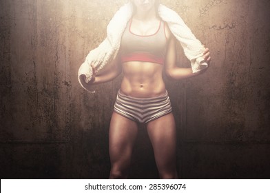 Exhausted Fit Young Woman After Hard Workout Using Her Soft White Towel And Proudly Posing In Front Of Gym Textured Background Wall