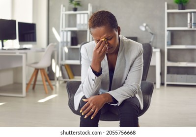 Exhausted And Frustrated Woman Is Working On Difficult Business Task And Has Bad Conversation. Tired African American Young Female Company Manager Sitting In Office In Front Of Webcam And Rubbing Eyes