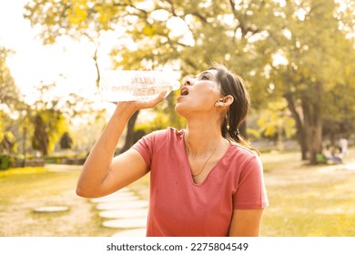 Exhausted Indian woman drink water in hot summer sunlight - heat stroke concept