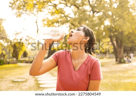 Exhausted Indian woman drink water in hot summer sunlight - heat stroke concept