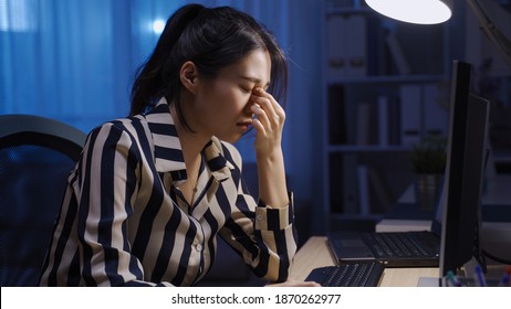 exhausted korean female employee working to a tight deadline while struggling with tired eyes in late night office. - Powered by Shutterstock