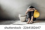 Exhausted little girl sitting on floor concrete wall background. child labor and exploitation